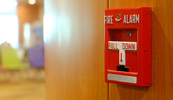 red manual fire alarm device on wooden wall