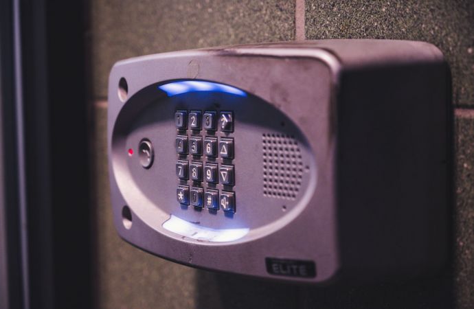 A modern home at dusk with visible security cameras mounted on corners, motion sensor lights illuminating the driveway, a